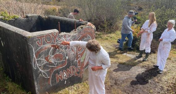 a group of people outside spray painting the word 'joy' on a wall