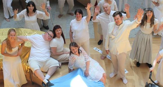 group of people smiling and waving from below wearing white costumes