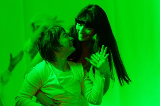two women in white smiling at each other in green light
