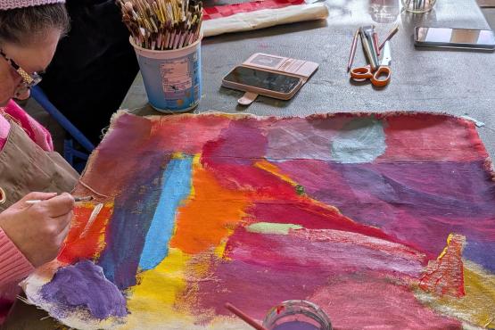 bright multi coloured painting with womans head and her hand on the left