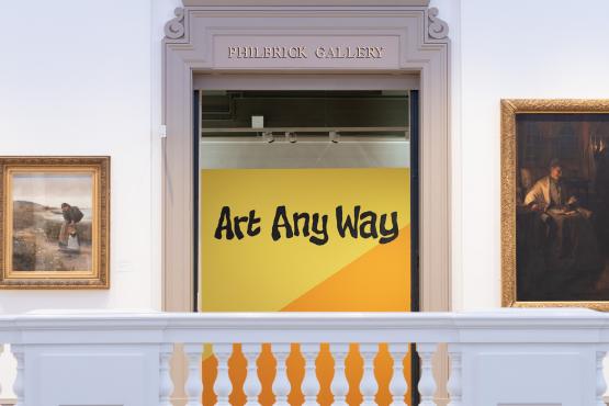 white doorway with yellow sign with black Art Any Way sign and paintings either side