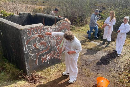 a group of people spray painting outside in white boiler suits