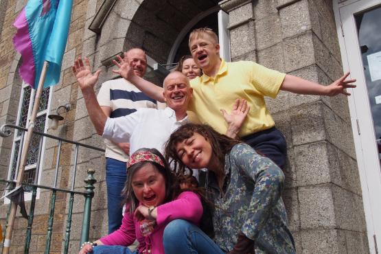 5 people standing on some steps in a crowd. Some are crouched and some are standing and they are all looking at the camera smiling