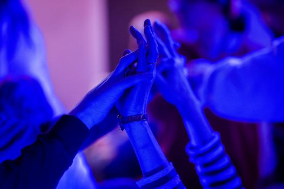 a photo of 2 people's hands holding high in the air. The light is blue.