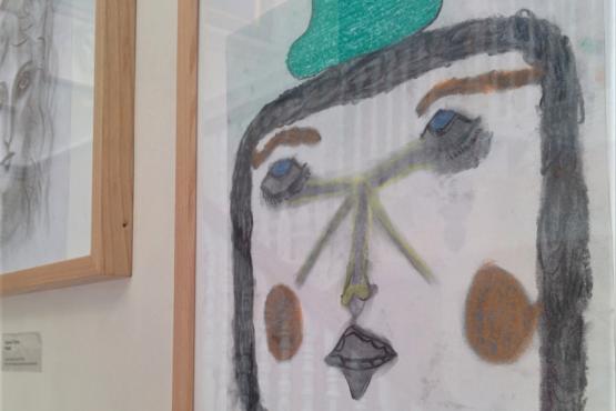 portrait painting framed in a gallery with another framed drawing in the background