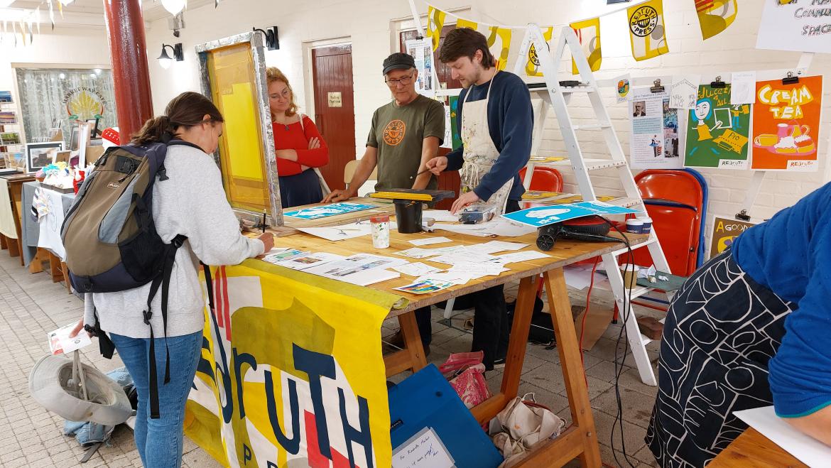 4 people screen printing around a table