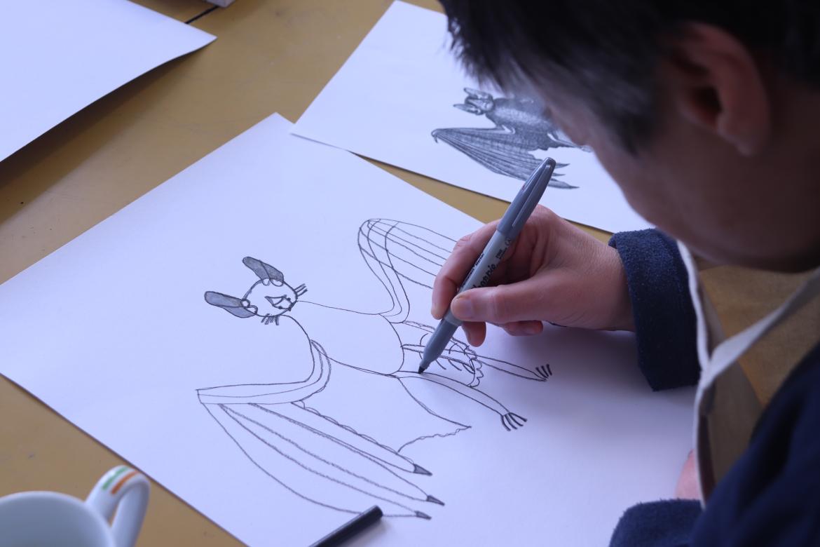 A person drawing a bat on paper with a pen