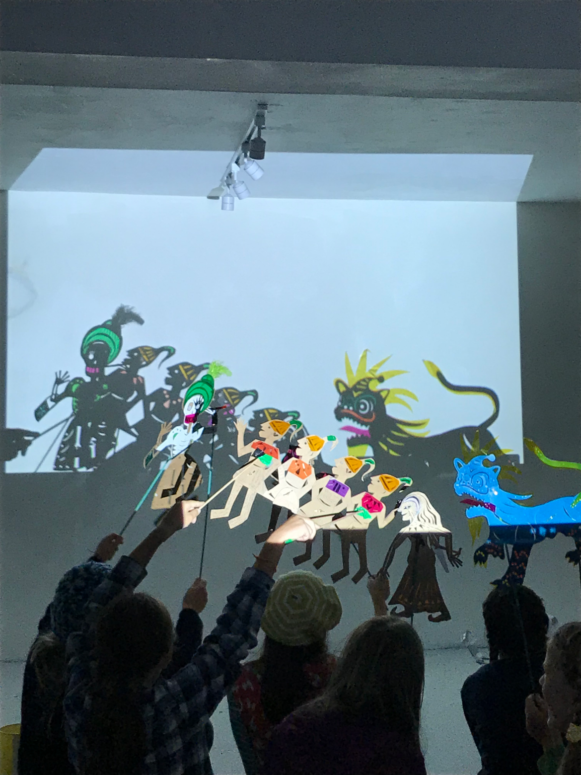 a group of children with their backs turned holding up shadow puppets