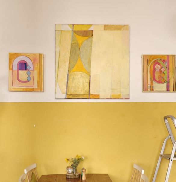 interior cafe with lower half yellow wall and 3 paintings