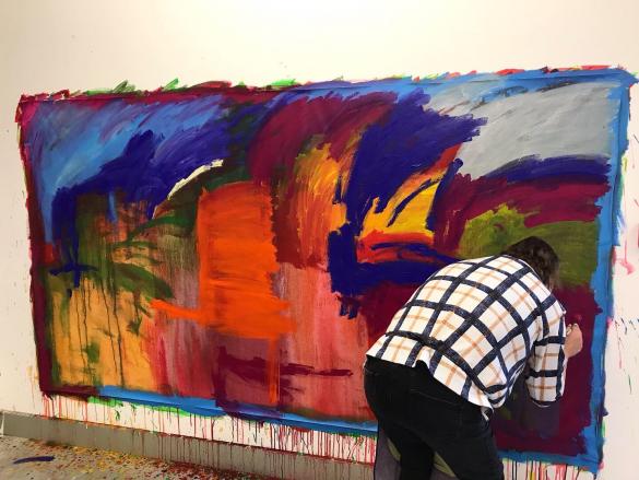 Janet Holland painting a large colourful abstract painting in Shallal Studios