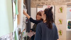 2 people looking at a screen print hanging at audience exploring work at Kresen Kernow Underworld exhibition 