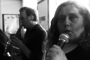 1 person singing into a microphone and 1 person playing the recorder