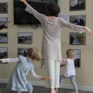 A person and 2 children dancing a gallery space. 
