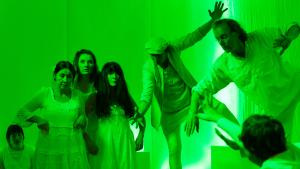 7 people dancing in a green lit space.