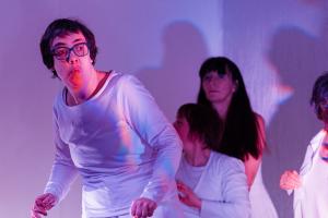 4 people dancing in a white space. All of them are wearing all white. 