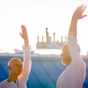 2 people in white upper bodies with one raised arm blue lower background light abov