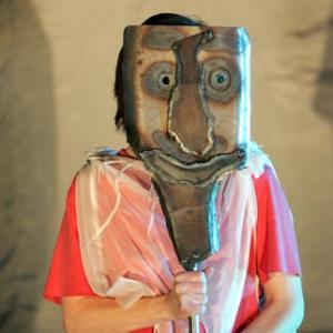 a person holding a metal mask over their face