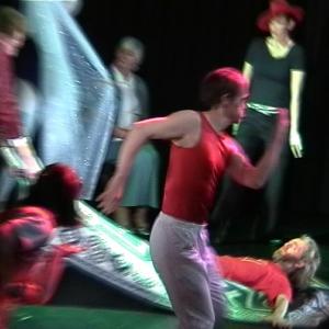 6 people dancing on stage. One person in the middle is lying on their back and being pulled along. The others are moving fast so appear slightly blurred