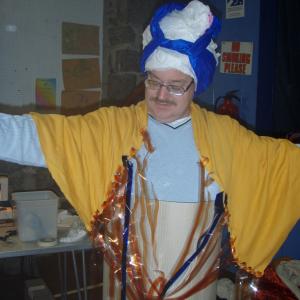 a person dressing in a yellow and blue costume. They have their arms raised out sideways. 