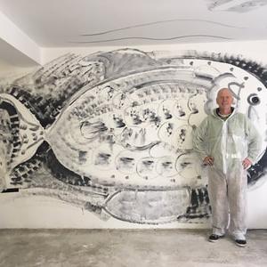 person standing in front of large black and white fish drawn on the wall