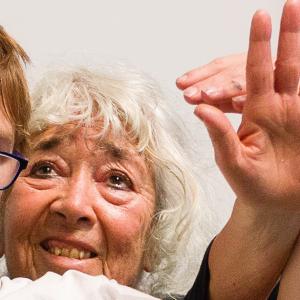head of woman with tanned skin and white hair looking up with hand up