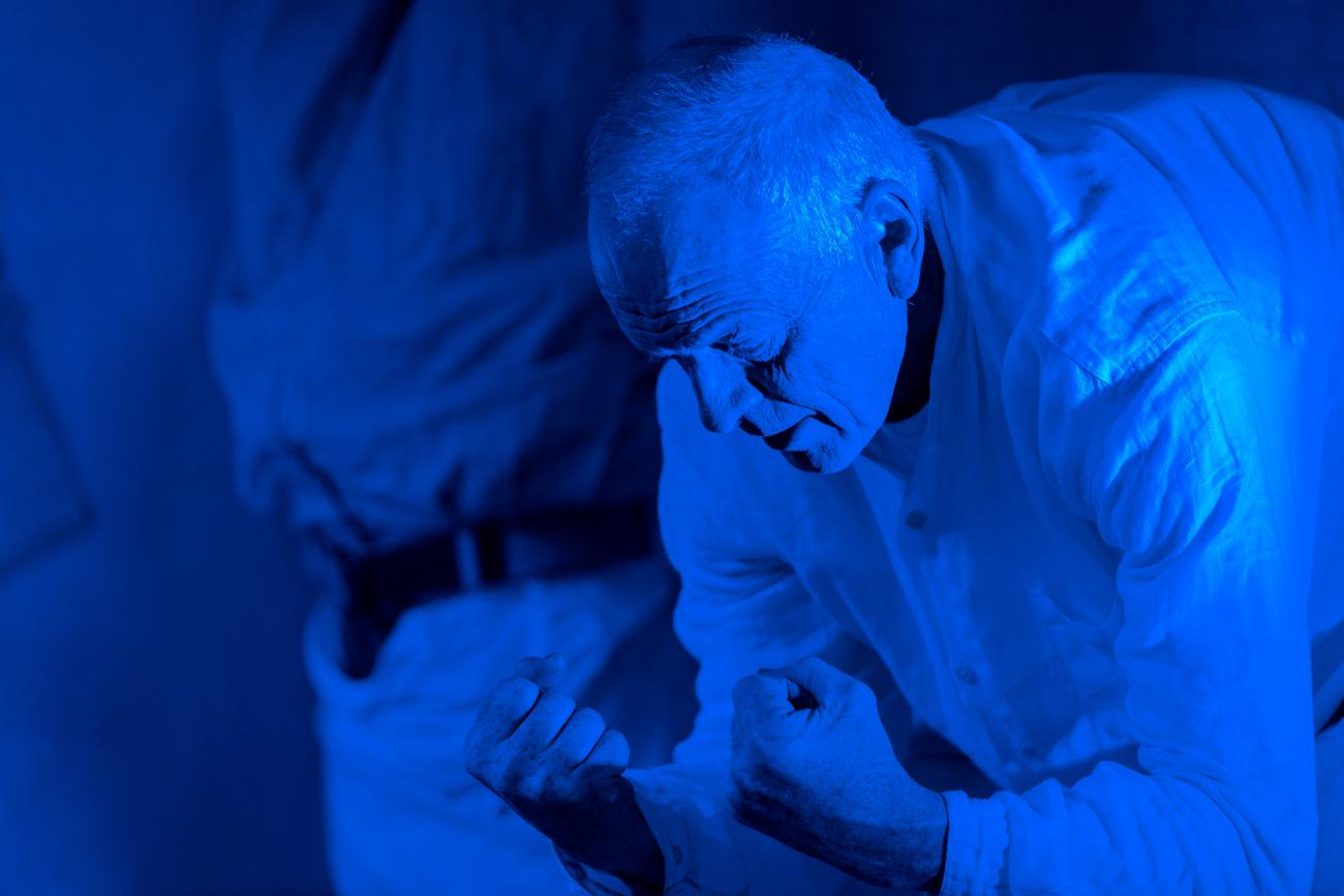 a person dancing in a blue lit space. They are bent forward with their fists clenched