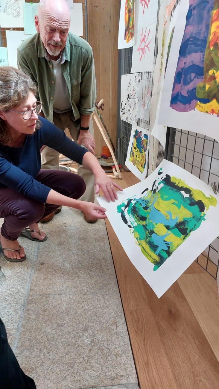 2 people looking at a screen print hanging at audience exploring work at Kresen Kernow Underworld exhibition 