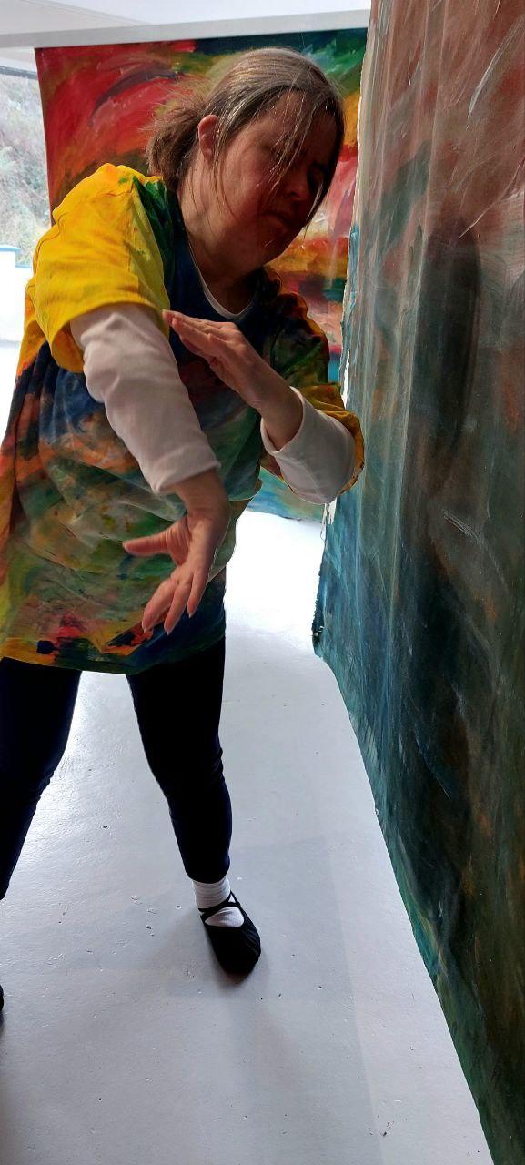 a person dancing in front of abstract colourful paintings 