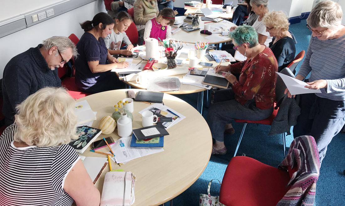a group of people working in sketchbooks around tables