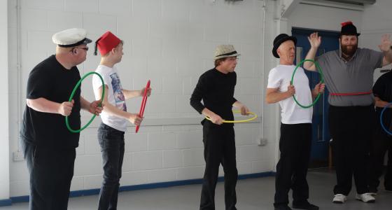 five people dancing in a room with coloured hoops in their hands